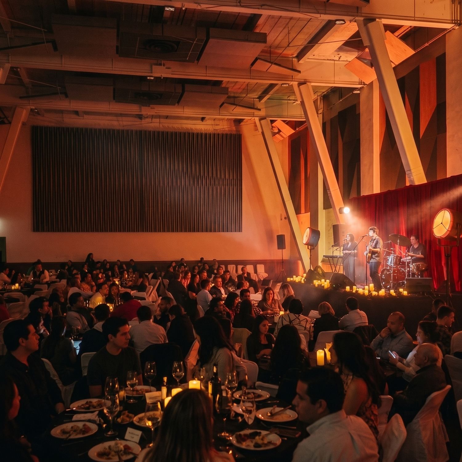 Concierto en el Salón Grand con banda en escenario y mesas iluminadas con velas